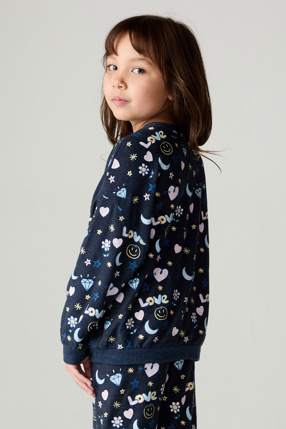 Side view of a girl wearing the Chaser Free Draw Girls Tee and matching pants on a neutral background