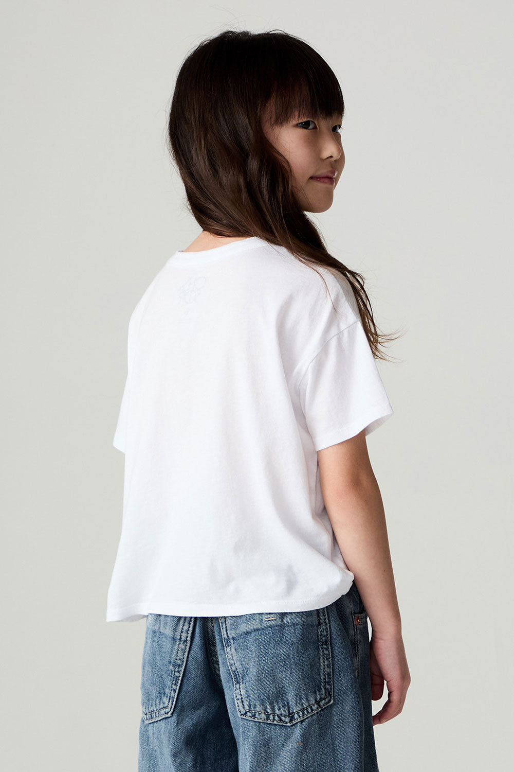 Back view of a girl wearing the Chaser Full Of Love Girls Tee on a neutral background with jeans