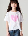 Front view of a girl wearing the Chaser Full Of Love Girls Tee on a neutral background with jeans and hands at sides of body