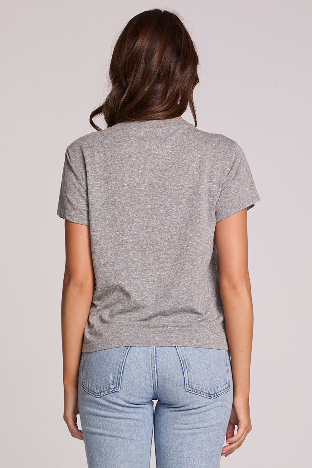 Back view of a woman wearing the Chaser Game Days Graphic Tee and jeans on a neutral background with arms lowered