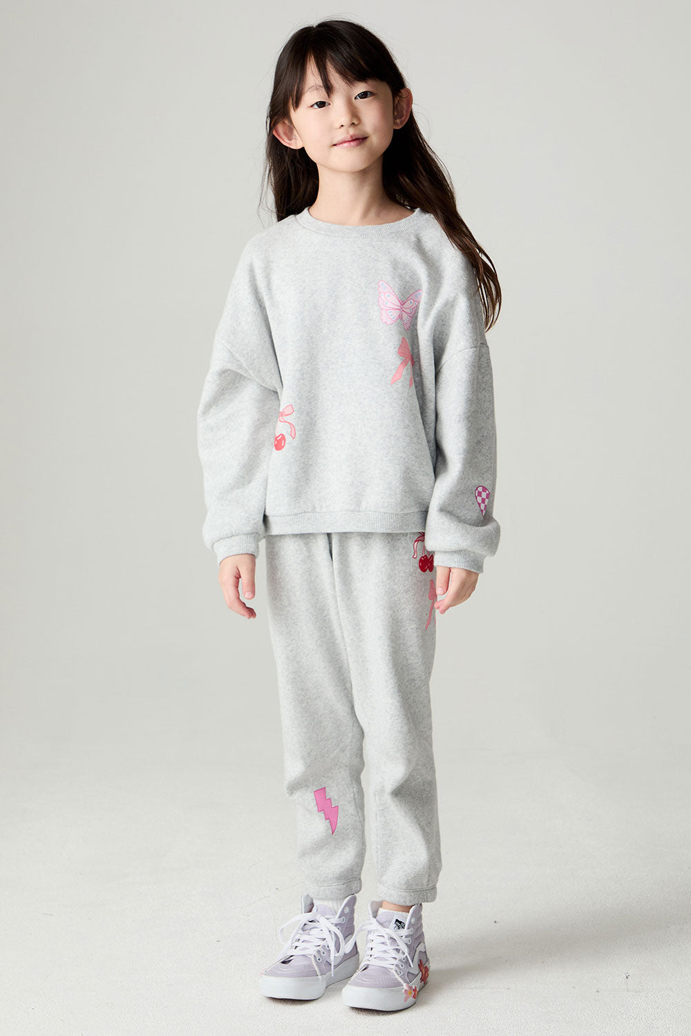 A full body front view of a girl wearing the Chaser irl Power Medley Girls Long Sleeve on a neutral background