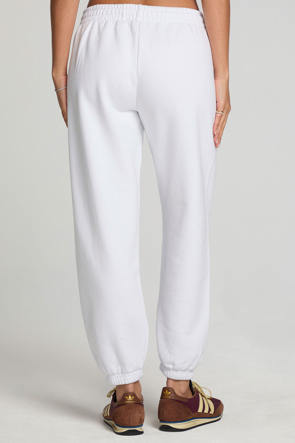 Back view of a woman wearing the Chaser  High Spirits Pants on a neutral background and arms at sides