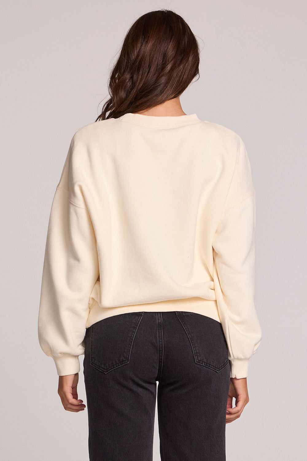 Back view of a woman wearing the Chaser How's Your Ap Res Sweatshirt on a neutral background with pants