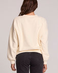Back view of a woman wearing the Chaser How's Your Ap Res Sweatshirt on a neutral background with pants
