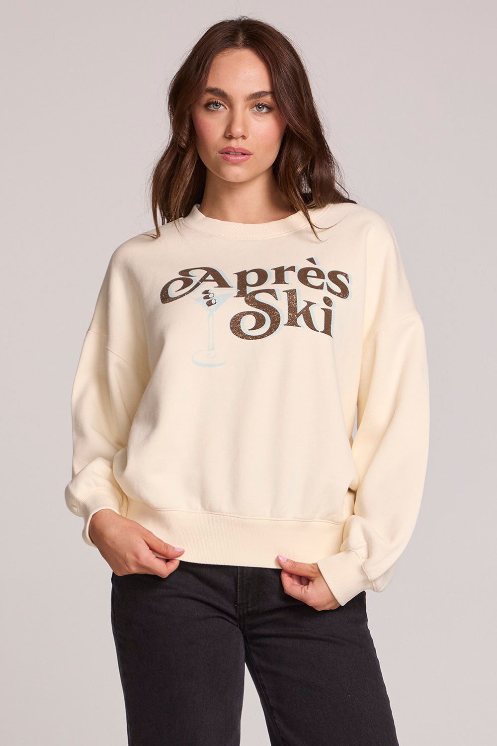 Front view of a woman wearing the Chaser How's Your Ap Res Sweatshirt on a neutral background with hands at hem
