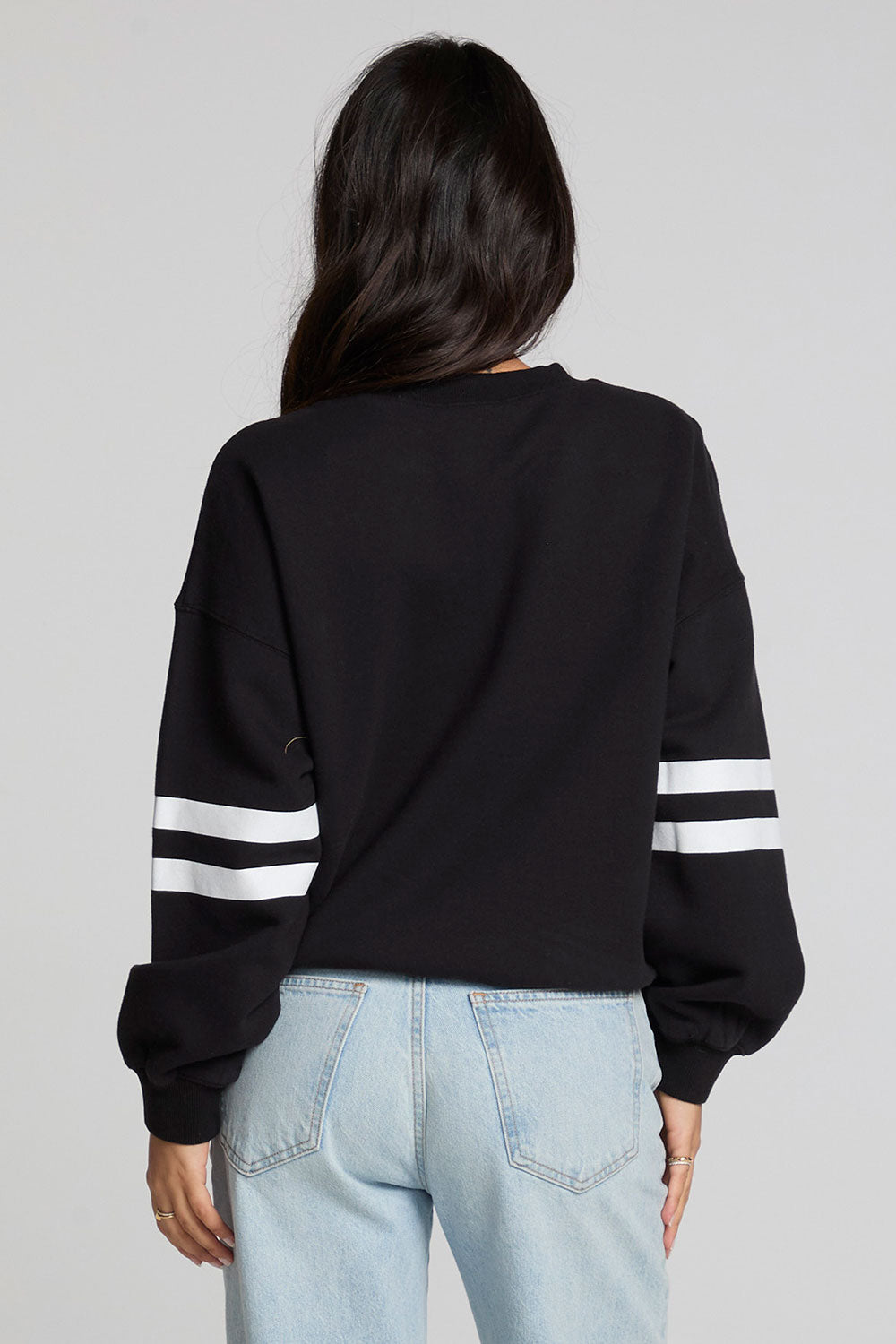 Back view of a woman wearing the Chaser I Love Sports Sweatshirt on a neutral background with jeans