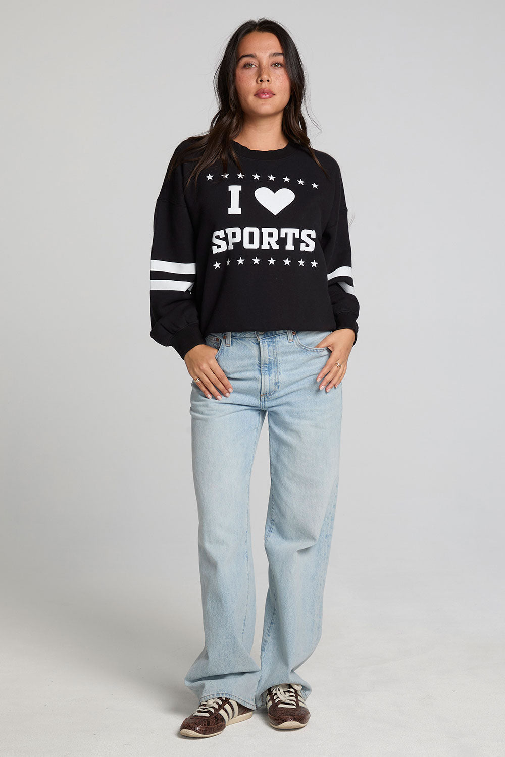 A full body front view of a woman wearing the Chaser I Love Sports Sweatshirt on a neutral background
