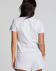 Back view of a woman wearing the Chaser  Isla Light Heather Grey Tee and matching shorts on a neutral background