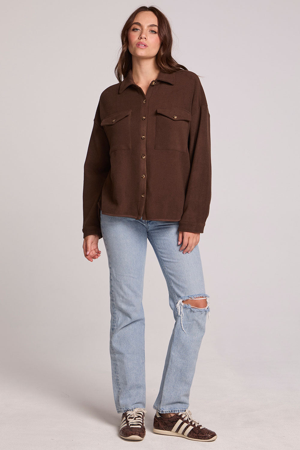 Full body front view of a woman wearing the Chaser Jaxxon Wood Brown Shacket and jeans on a neutral background with arms at sides