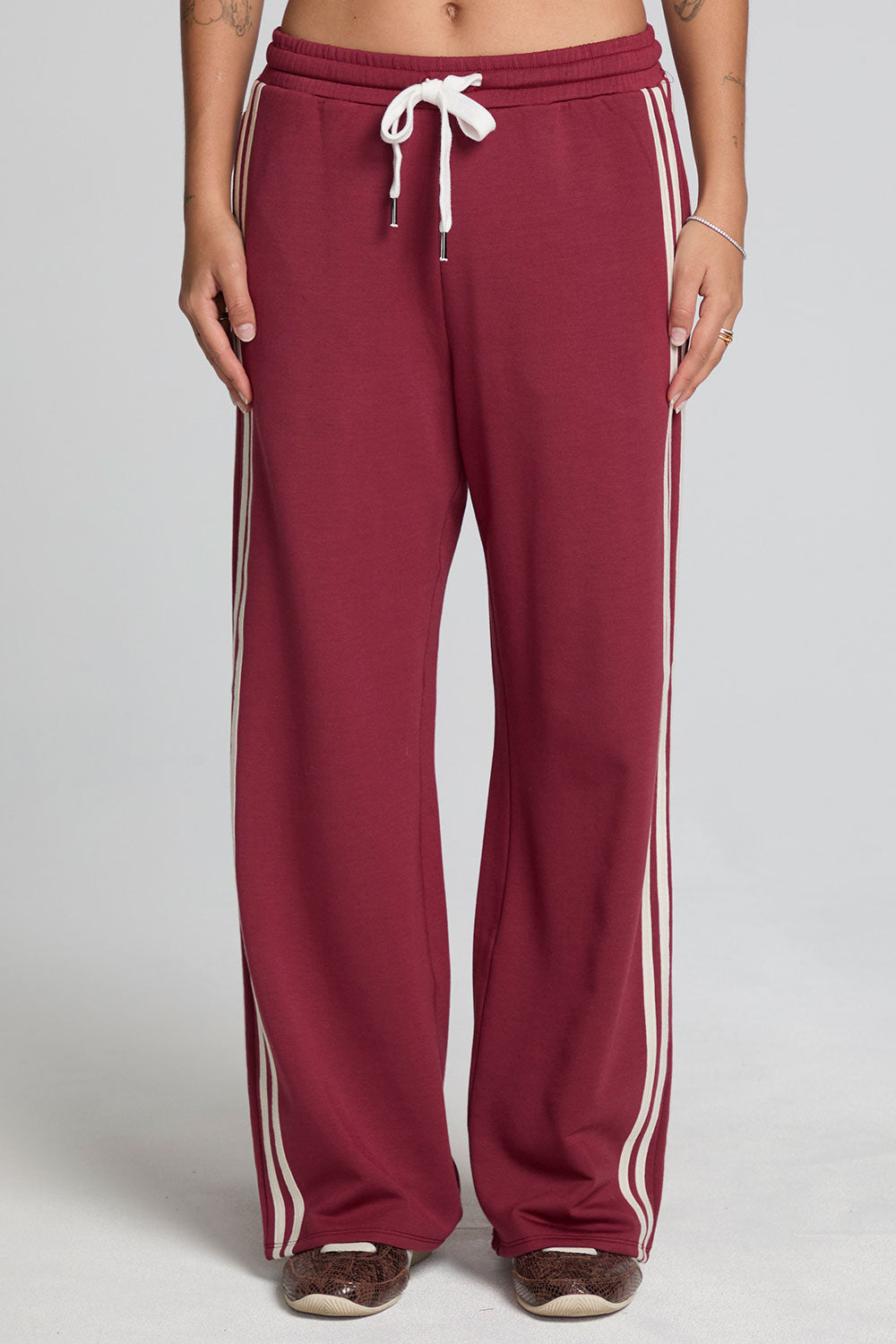 Front view of a woman wearing the Chaser Jessee Brick Red Trackpants on a neutral background with arms lowered