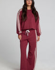 A full body front view of a woman wearing the Chaser Jessee Brick Red Trackpants on a neutral background