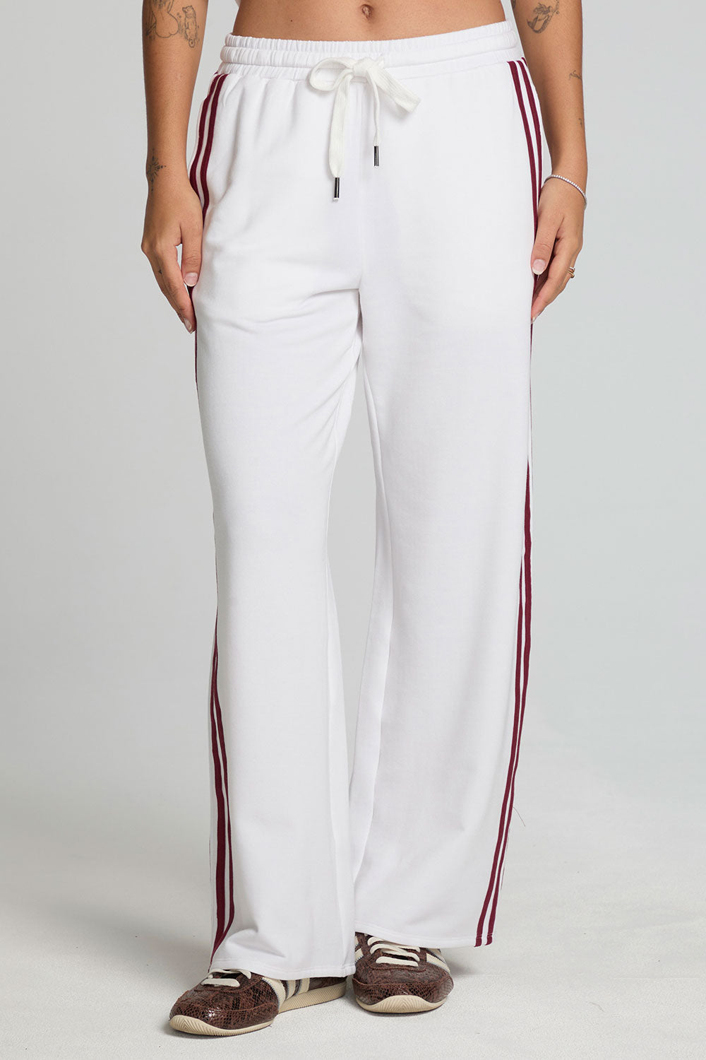 Front view of a woman wearing the Chaser Jessee Cloud White Trackpants on a neutral background with arms down at sides