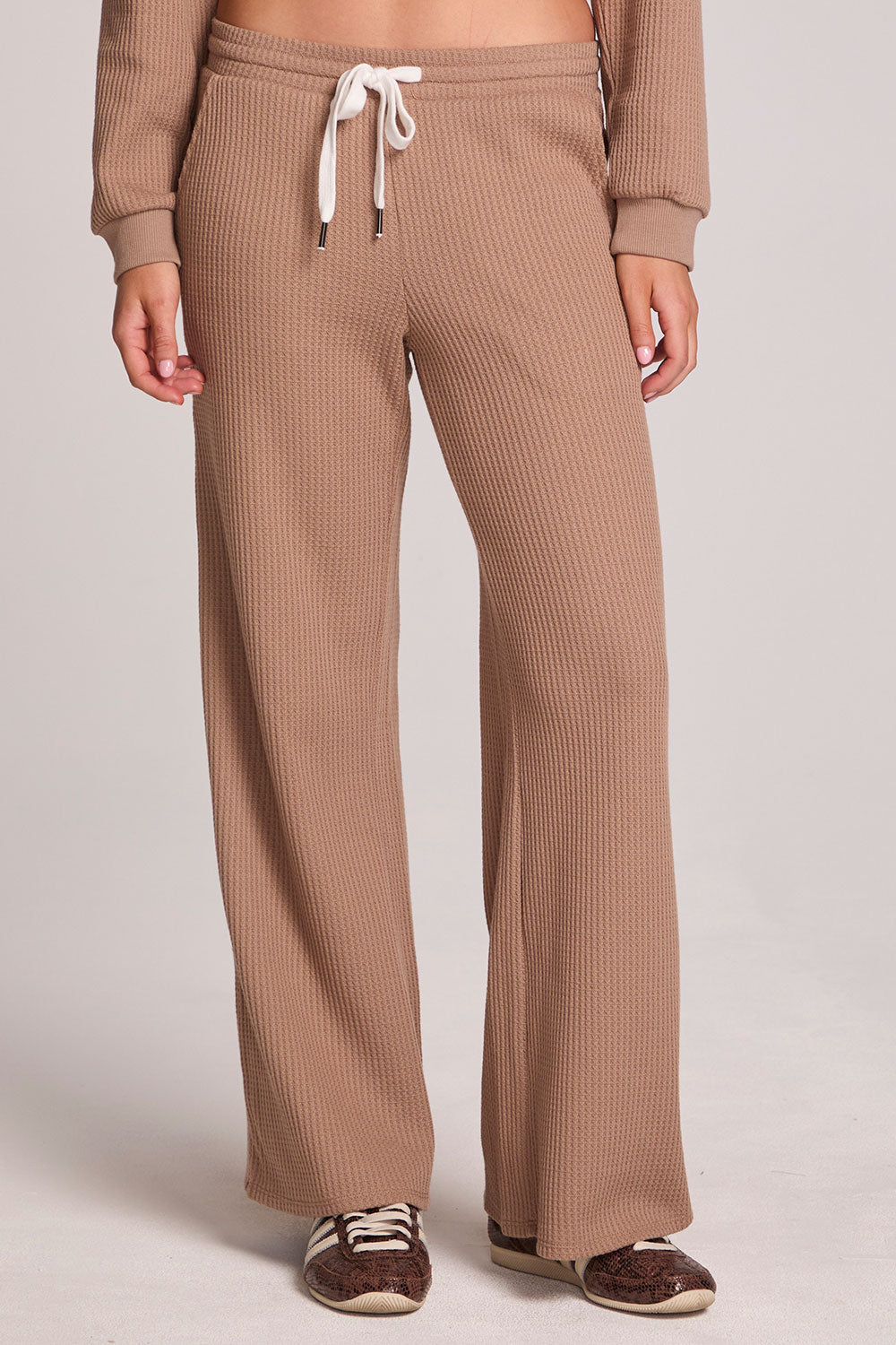 Front view of a woman wearing the Chaser Jorgia Camel Pants on a neutral background with shoes