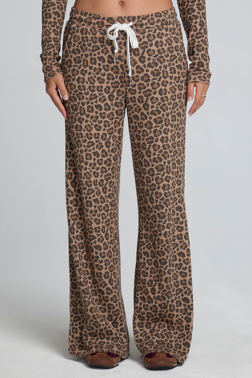 Front view of a woman wearing the Chaser  Jorgia Leopard Pant on a neutral background with brown shoes