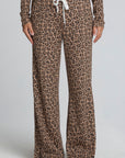 Front view of a woman wearing the Chaser  Jorgia Leopard Pant on a neutral background with brown shoes