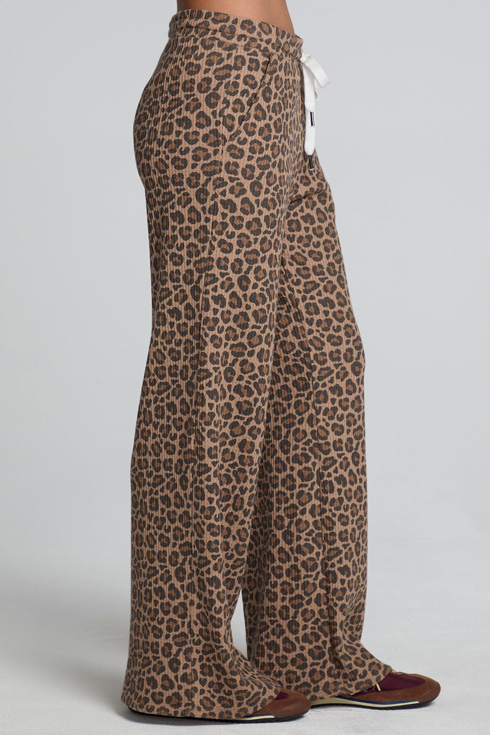 Side view of a woman wearing the Chaser  Jorgia Leopard Pant on a neutral background with shoes