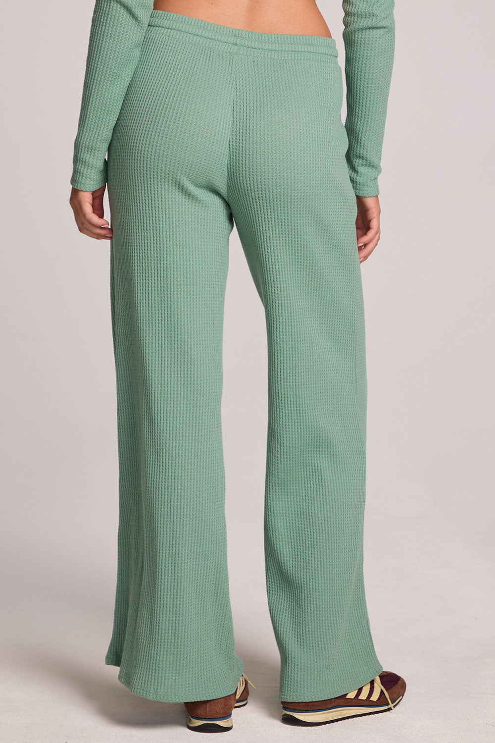 Back view of a woman wearing the Chaser  Jorgia Verdelle Pants on a neutral background