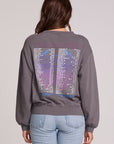 Back view of a woman wearing the Chaser Journey 1983 Tour Sweatshirt on a neutral background with jeans