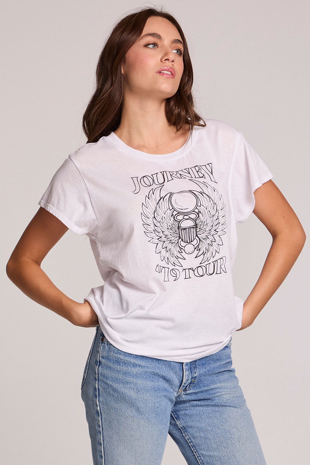 Front view of a woman wearing the Chaser Journey 79 Tour Tee on a neutral background with hands on her hips