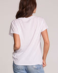 Back view of a woman wearing the Chaser Journey 79 Tour Tee on a neutral background with one handson her hips