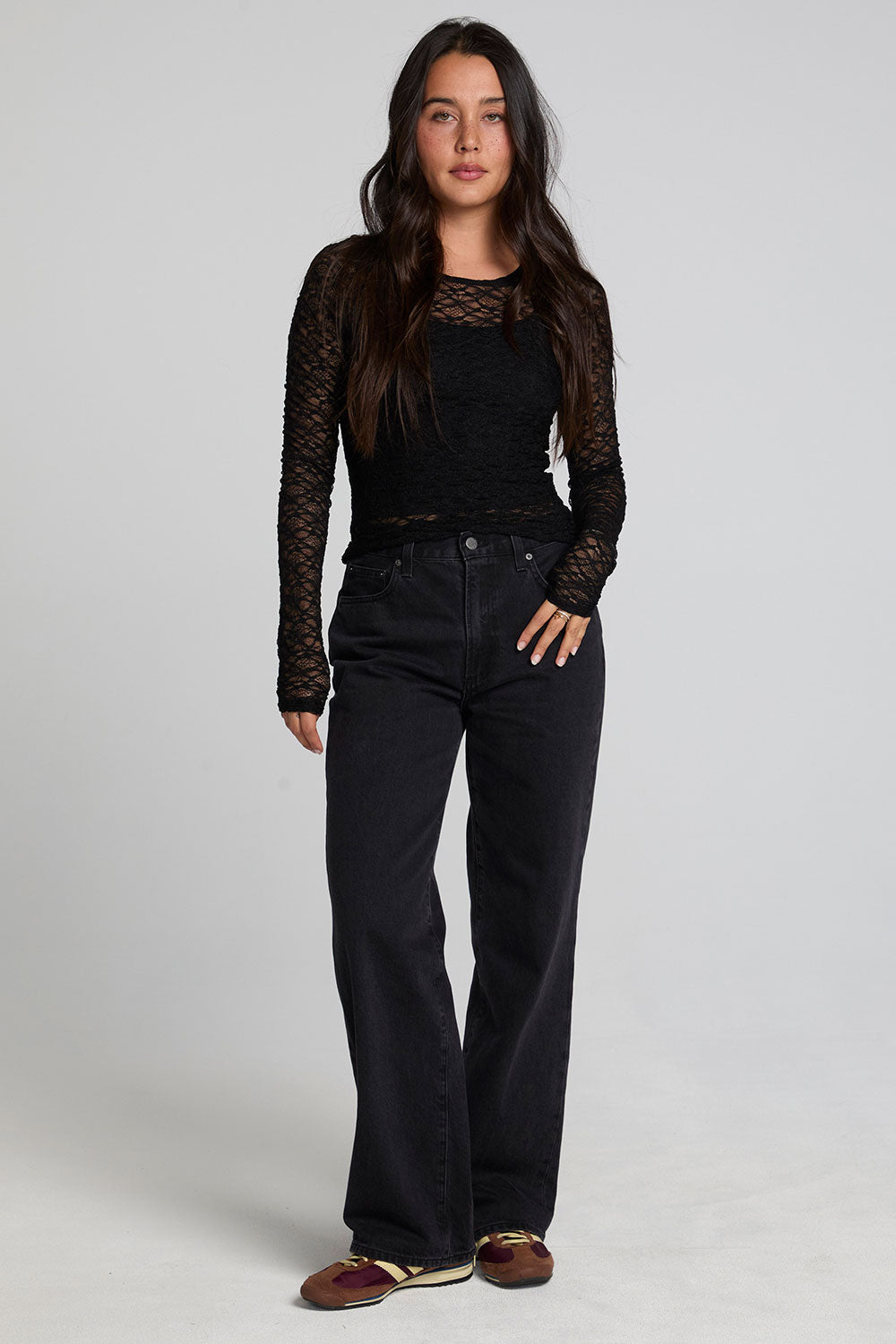 A full body front view of a woman wearing the Chaser Kevin Black Longsleeve on a neutral background