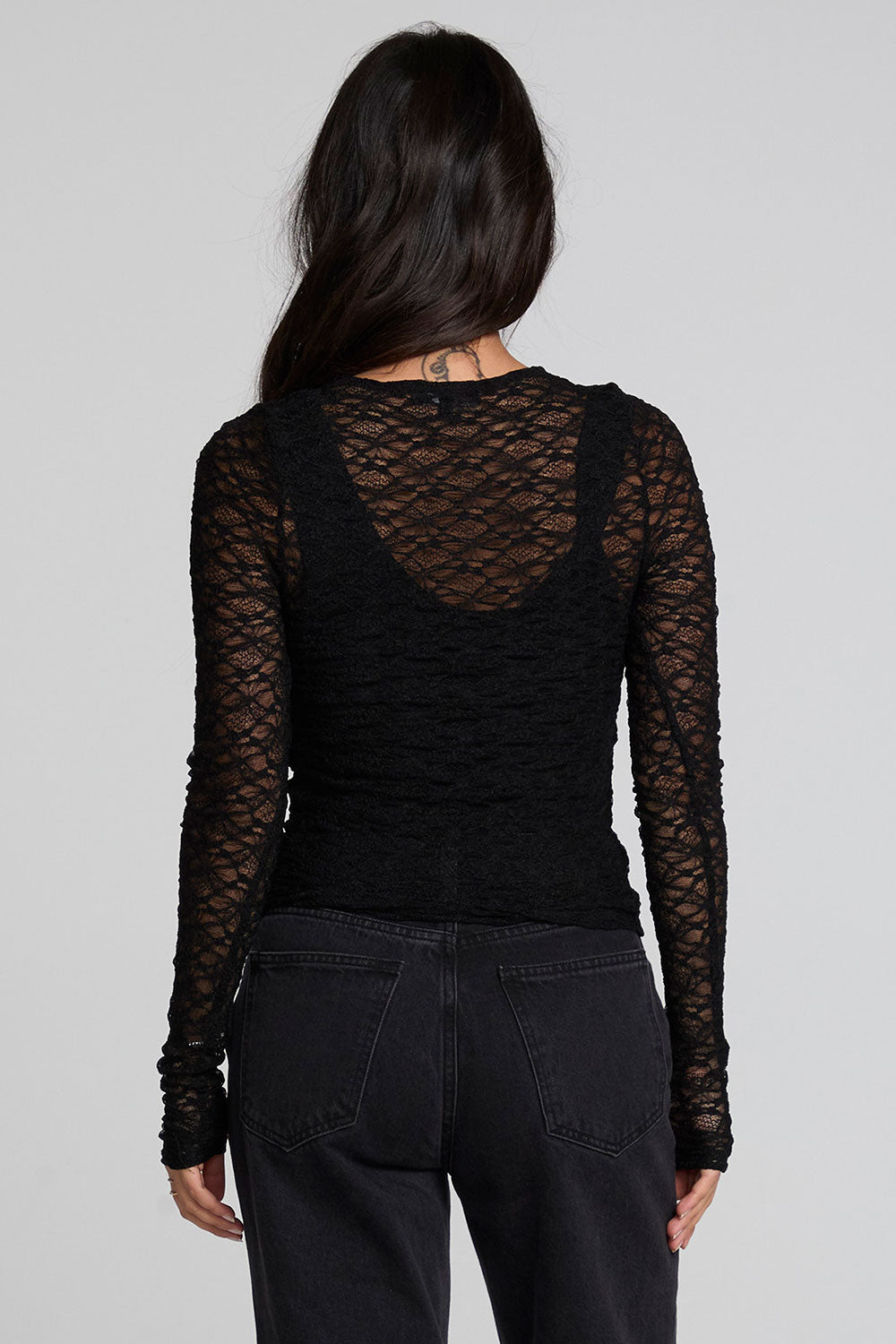 Back view of a woman wearing the Chaser Kevin Black Longsleeve on a neutral background with pants