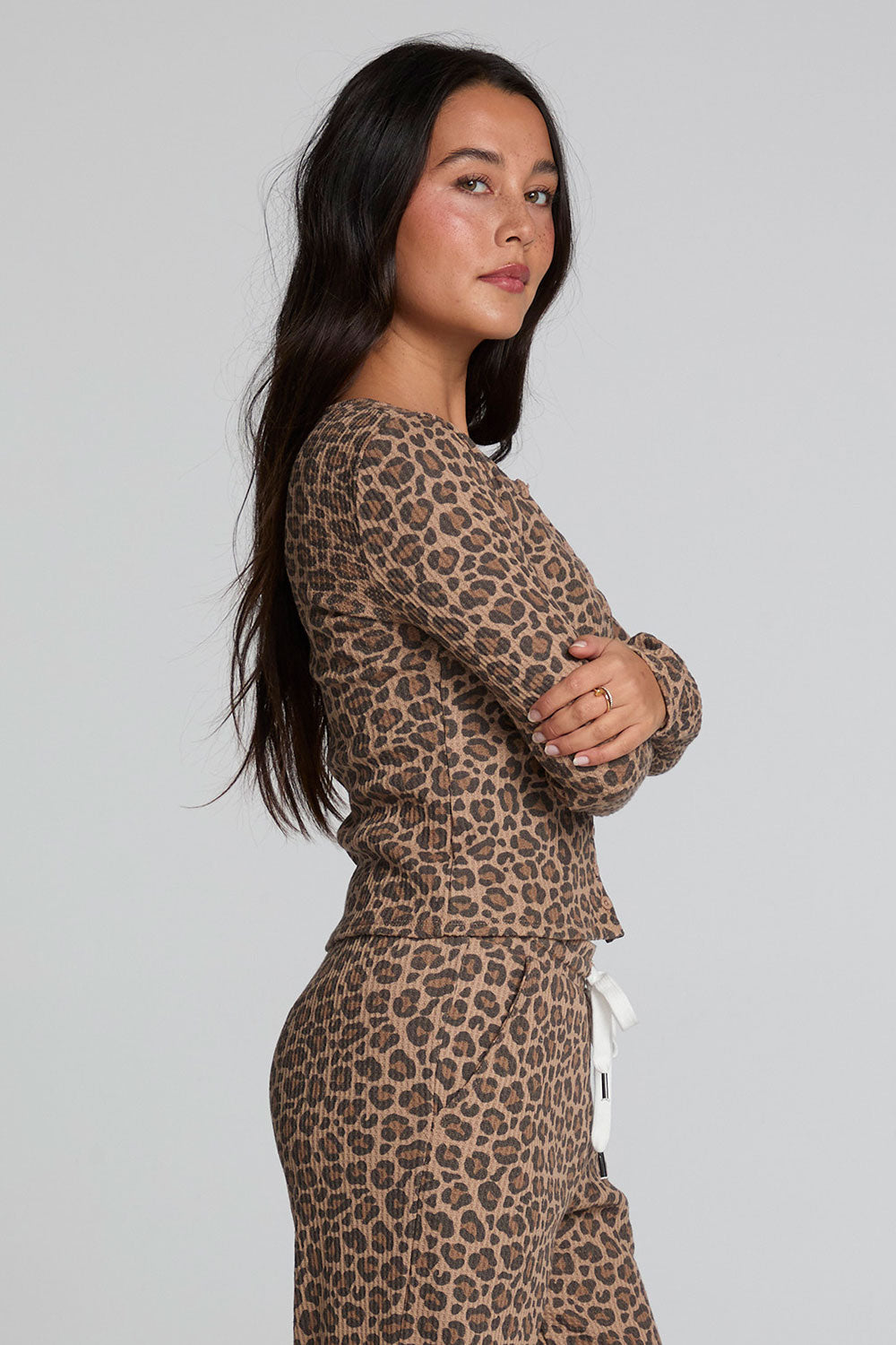 Side view of a woman wearing the Chaser  Klara Leopard Button Down Top on a neutral background with matching pants