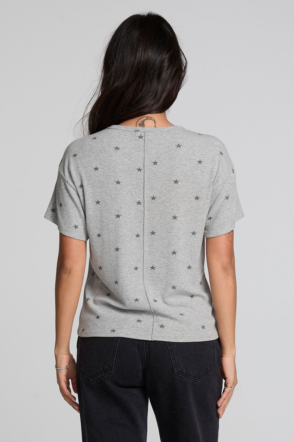 Back view of a woman wearing the Chaser Leonor Light Heather Grey Tee on a neutral background with black pants