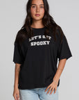 Front view of a woman wearing the Chaser Let's Get Spooky Tee on a neutral background with jeans and hands on leg