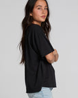 Side view of a woman wearing the Chaser Let's Get Spooky Tee on a neutral background with blue jeans