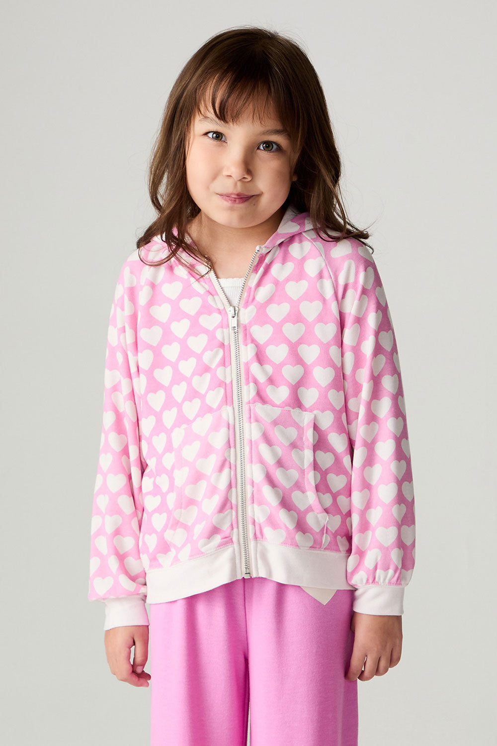 Front view of a girl wearing the Chaser Love Is Everywhere Girls Hoodie and pink pants