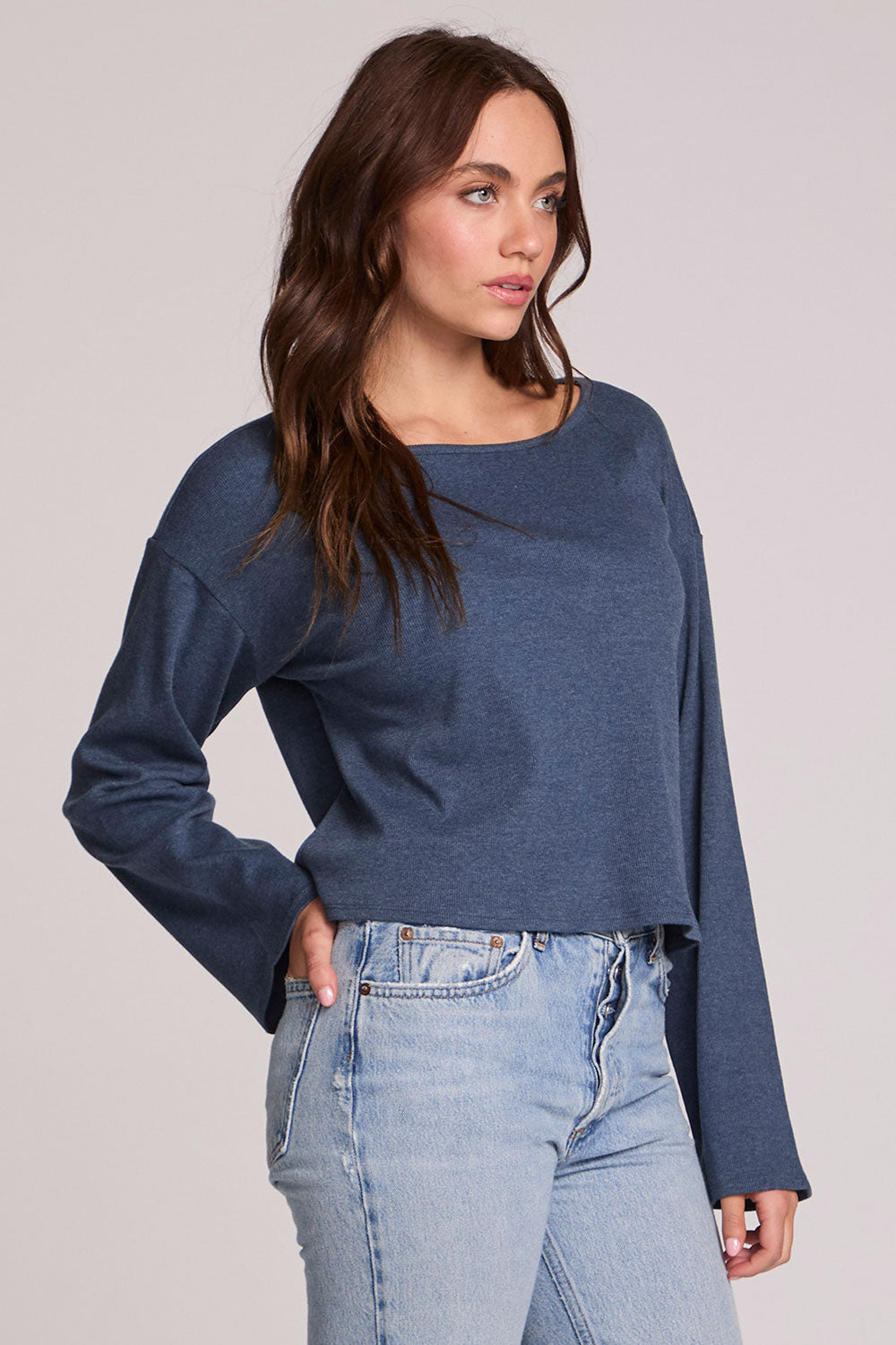 Side view of a woman wearing the Chaser Lunnah Dark Denim Top and jeans on a neutral background 