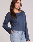 Side view of a woman wearing the Chaser Lunnah Dark Denim Top and jeans on a neutral background 