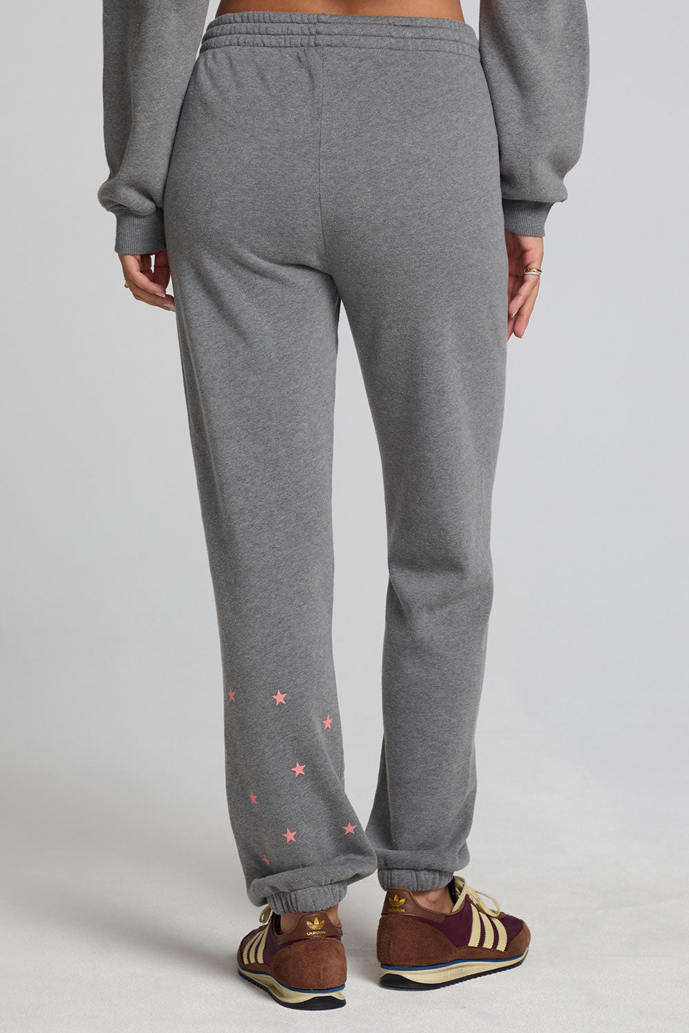 Back view of a woman wearing the Chaser Mini Star Glaze Pants and matching grey sweatshirt on a neutral background