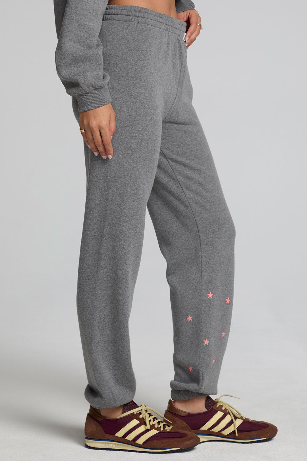 Side view of a woman wearing the Chaser Mini Star Glaze Pants and sweatshirt on a neutral background