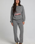 Full body front view of a woman wearing the Chaser Mini Star Glaze Sweatshirt on a neutral background in matching grey sweatpants