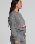 Side view of a woman wearing the Chaser  Mini Star Glaze Sweatshirt on a neutral background