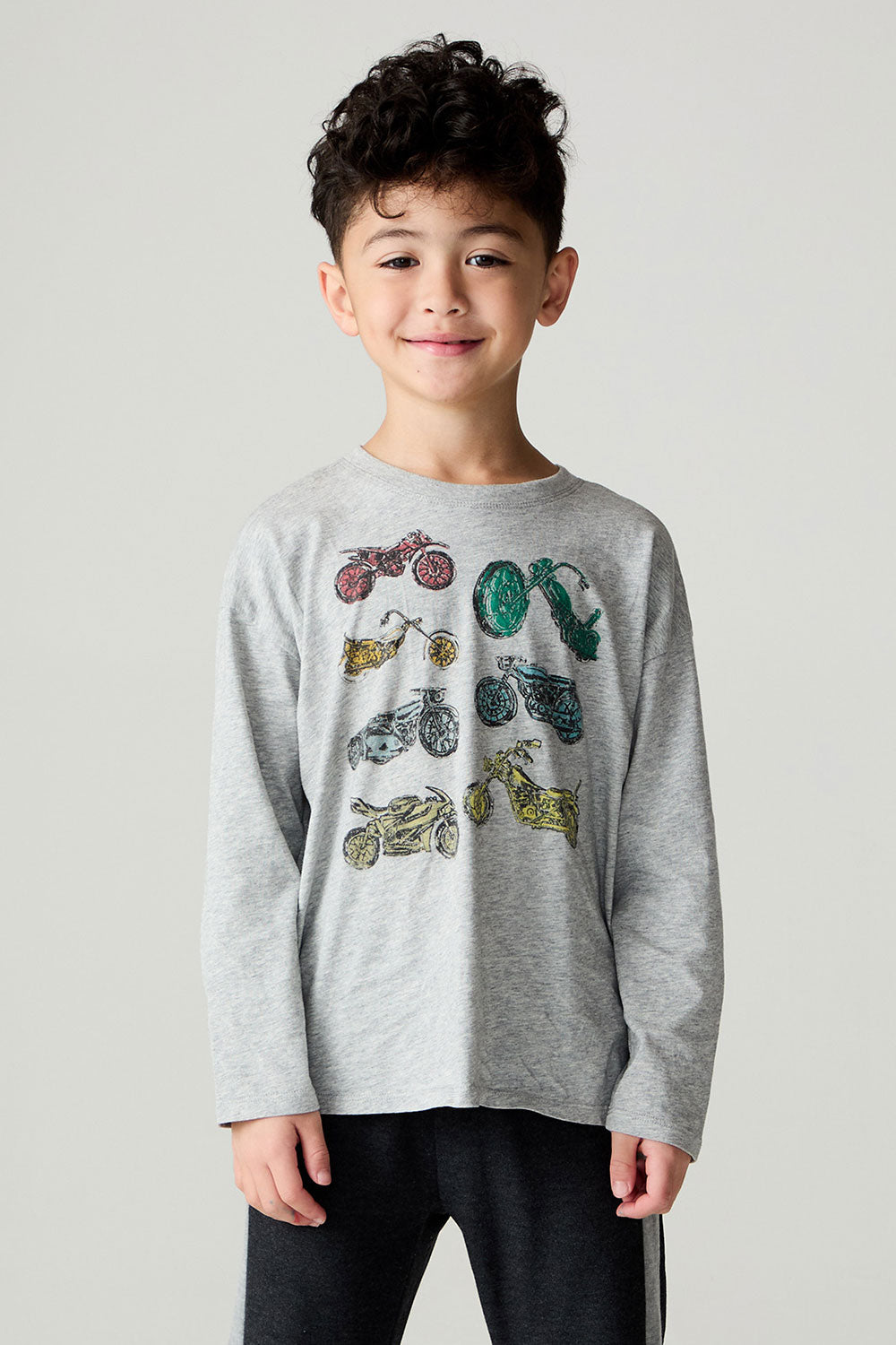Front view of a boy wearing the Chaser Moto Boys Tee and black pants on a neutral background with hands at sides