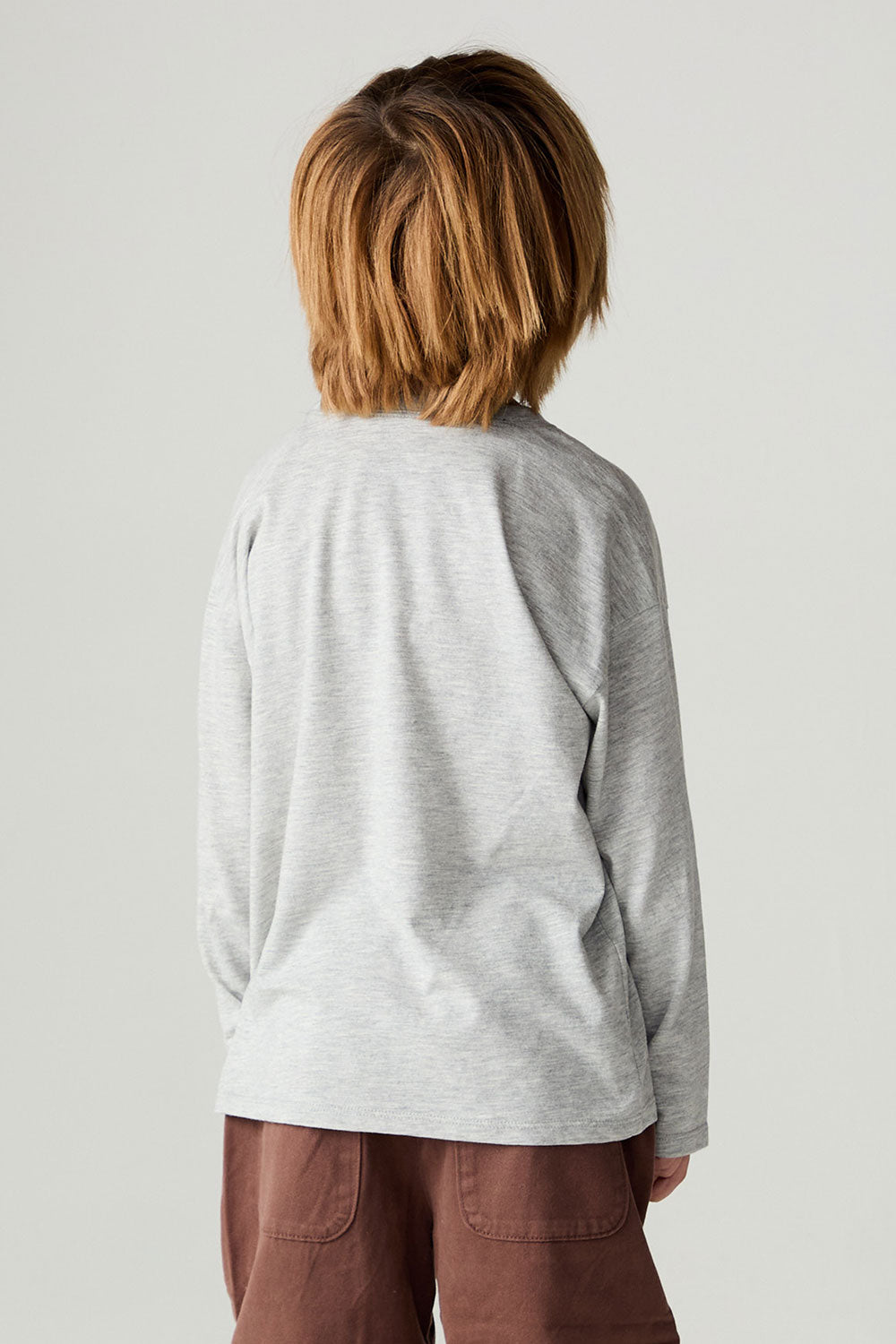 Back view of a boy wearing the Chaser Moto Patches Boys Tee on a neutral background with arms lowered
