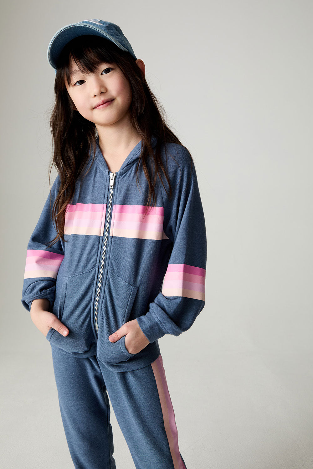 Full body front view of a girl wearing the Chaser Multi Stripes Girls Hoodie on a neutral background with hands in pockets