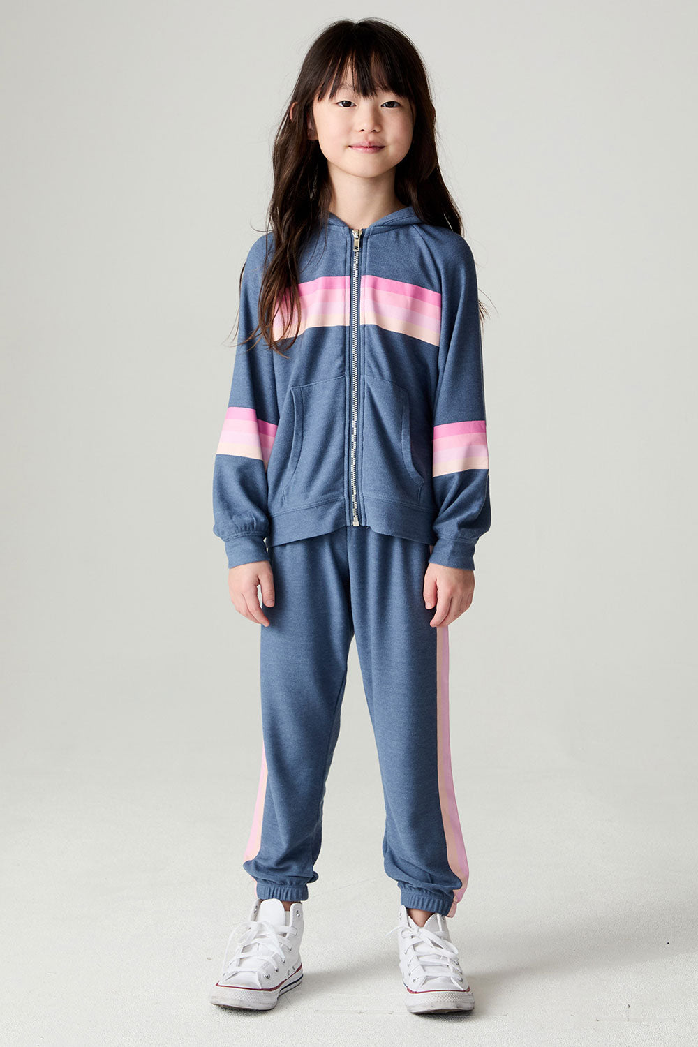 Seated girl wearing the Chaser Multi Stripes Girls Jogger on a neutral background with matching pants