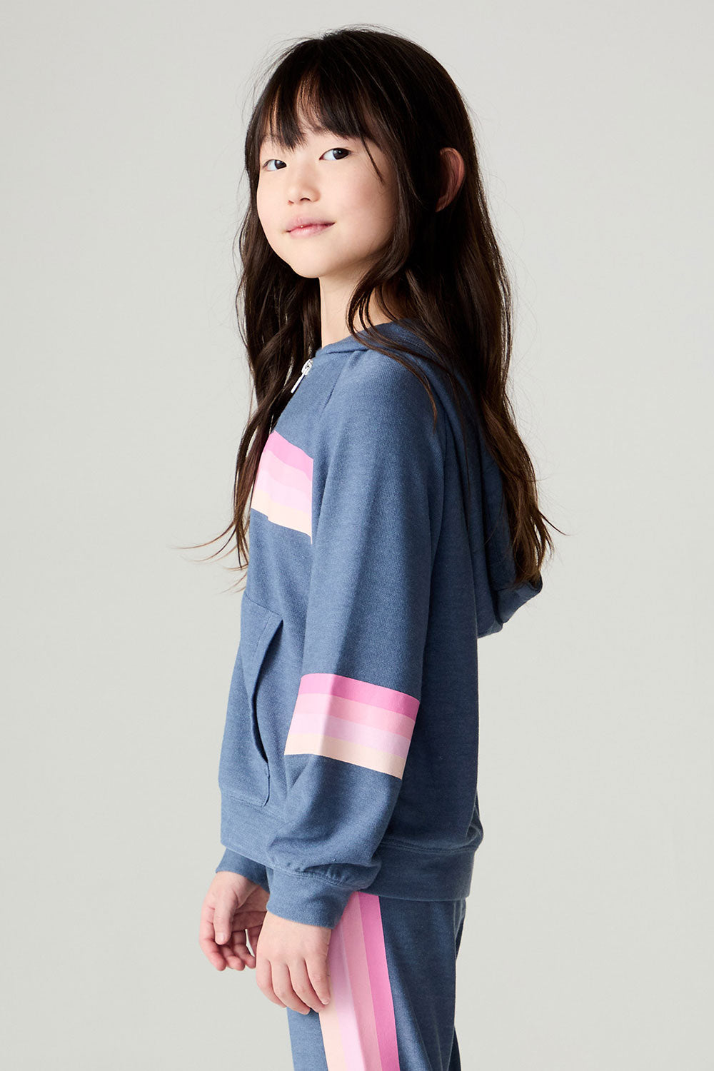 Side view of a girl wearing the Chaser Multi Stripes Girls Hoodie on a neutral background with arms at sides