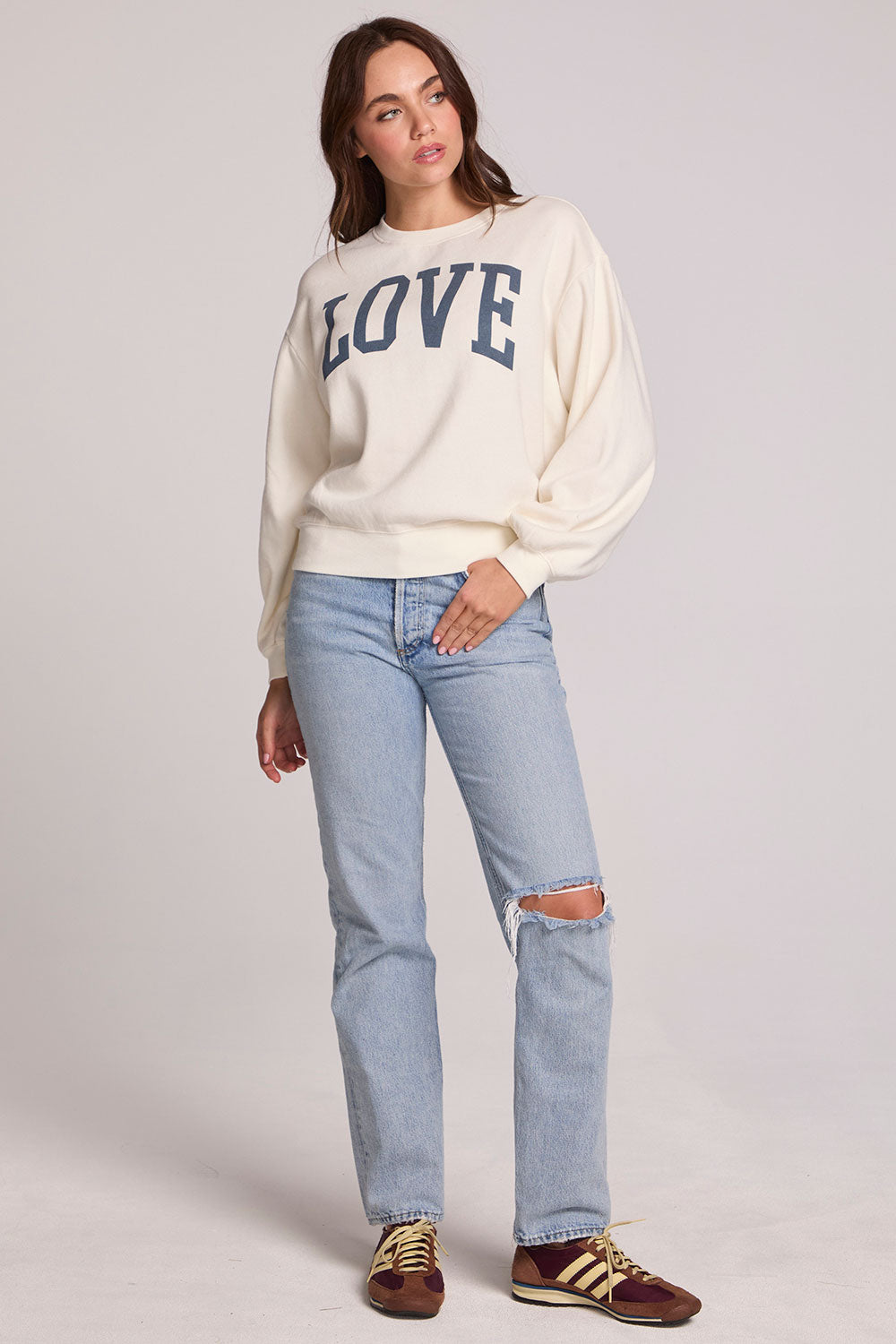 Full body view of a woman wearing the Chaser Navy Love Pullover Sweater and jeans on a neutral background 