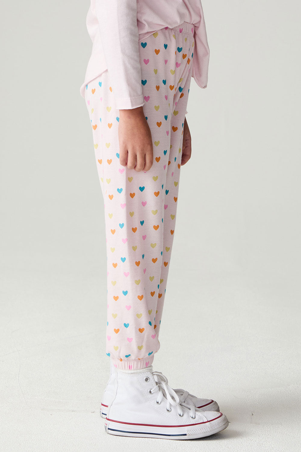 Side view of a girl wearing the Chaser Party Hearts Girls Jogger on a neutral background with hands at sides