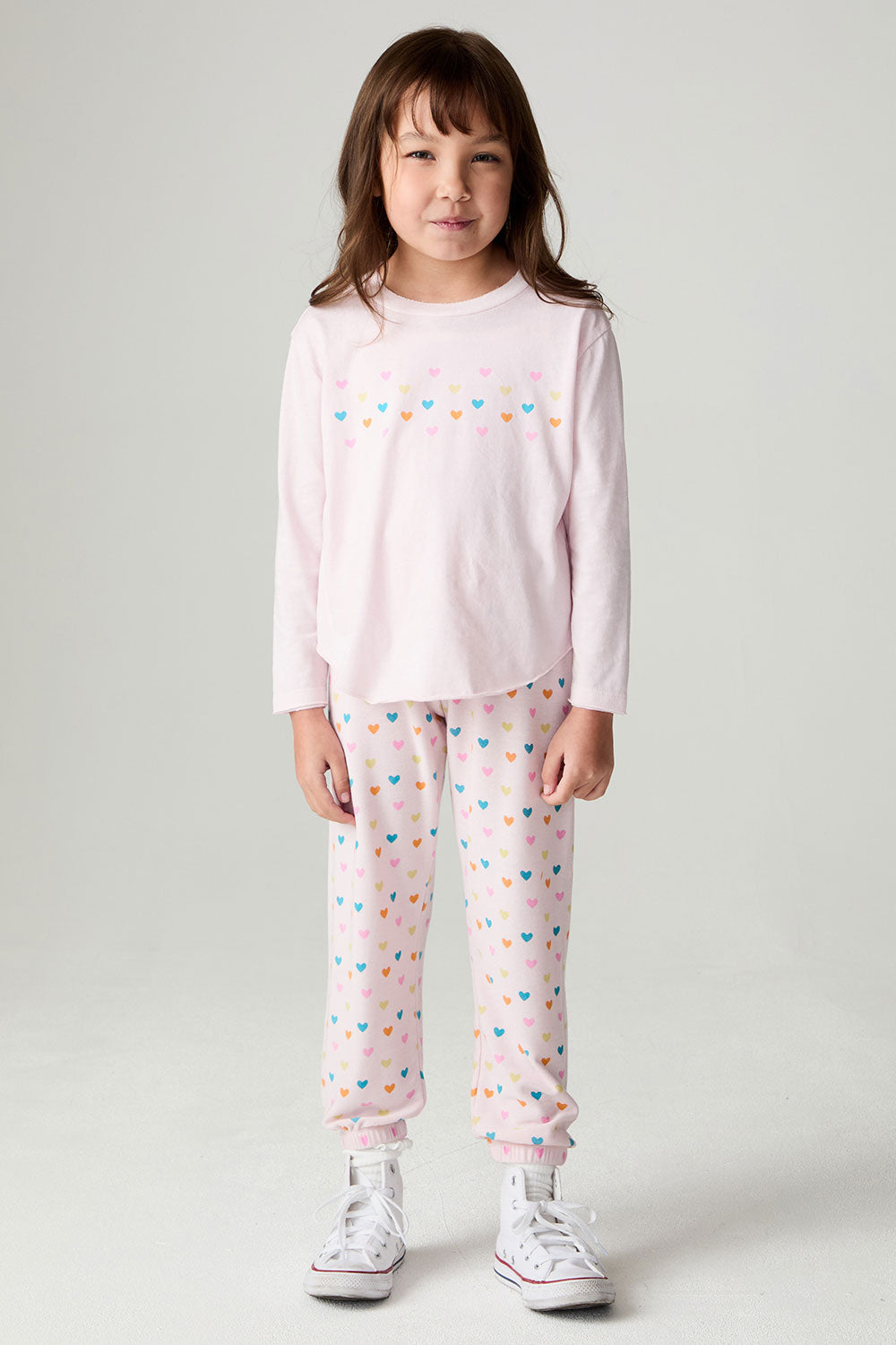 Full body front view of a girl wearing the Chaser Party Hearts Girls Jogger on a neutral background with hands at sides and matching shirt