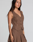 Side angle view of a woman wearing the Chaser Pea Choco Check Waistcoat and matching skirt on a neutral background