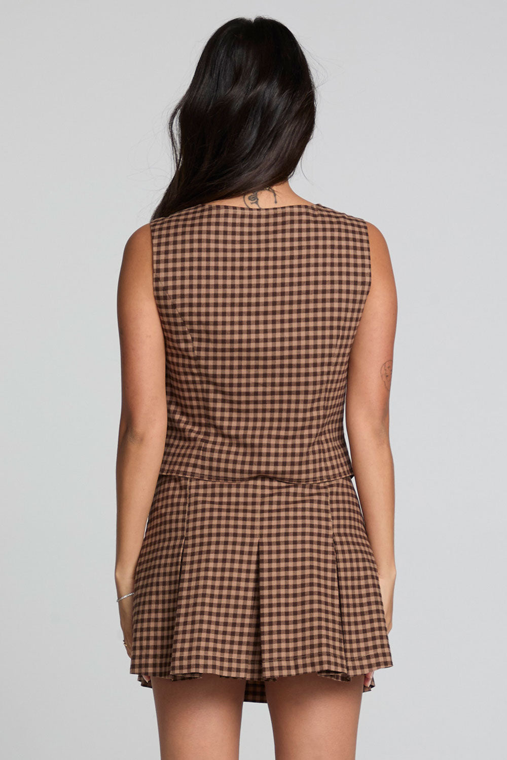Back view of a woman wearing the Chaser Pea Choco Check Waistcoat and skirt on a neutral background
