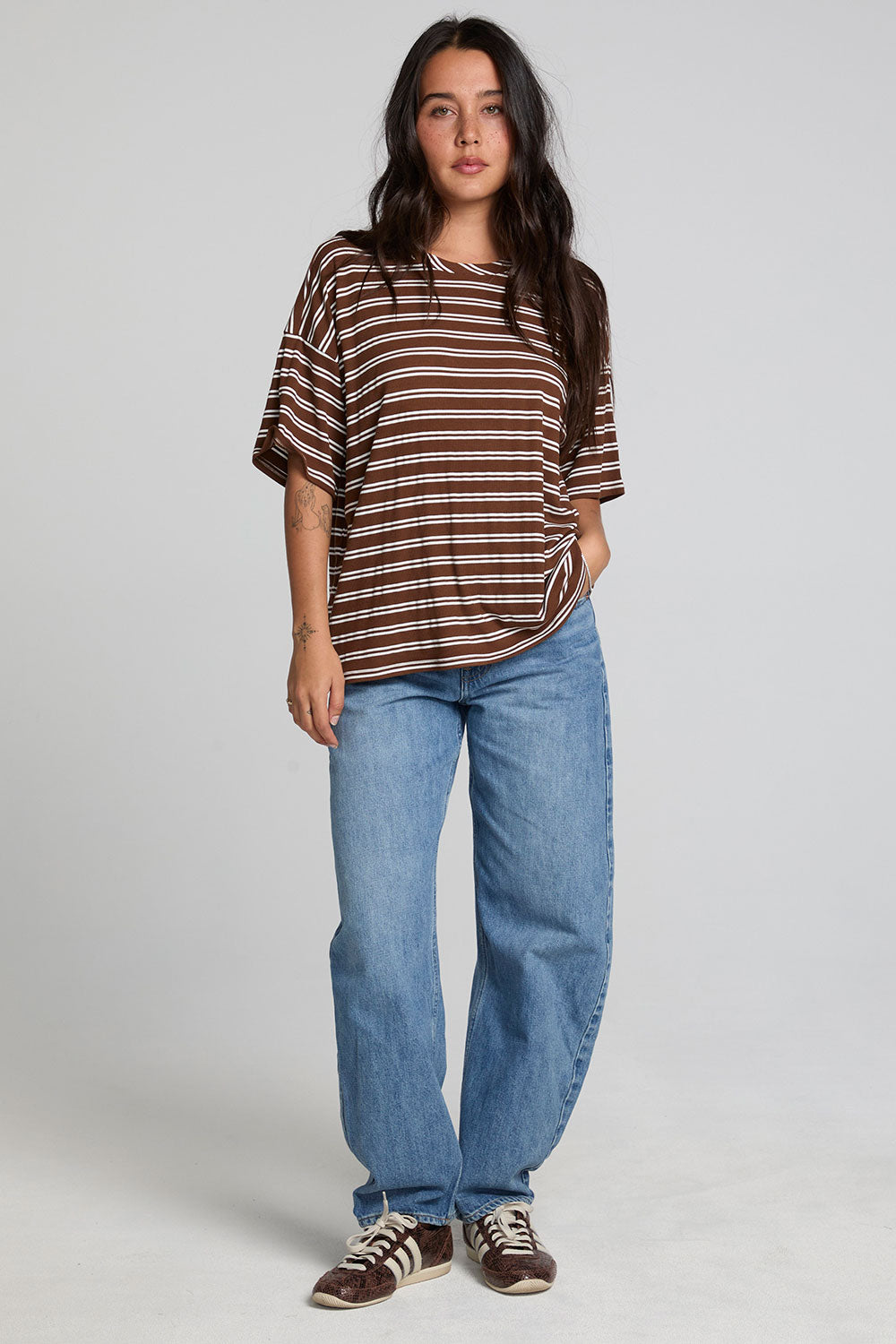 A full body front view of a woman wearing the Chaser Peri Nutty Brown Stripe Tee on a neutral background
