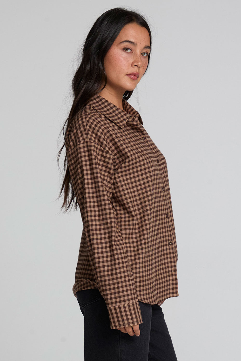 Side view of a woman wearing the Chaser Pine button down on a neutral background with arms at her sides
