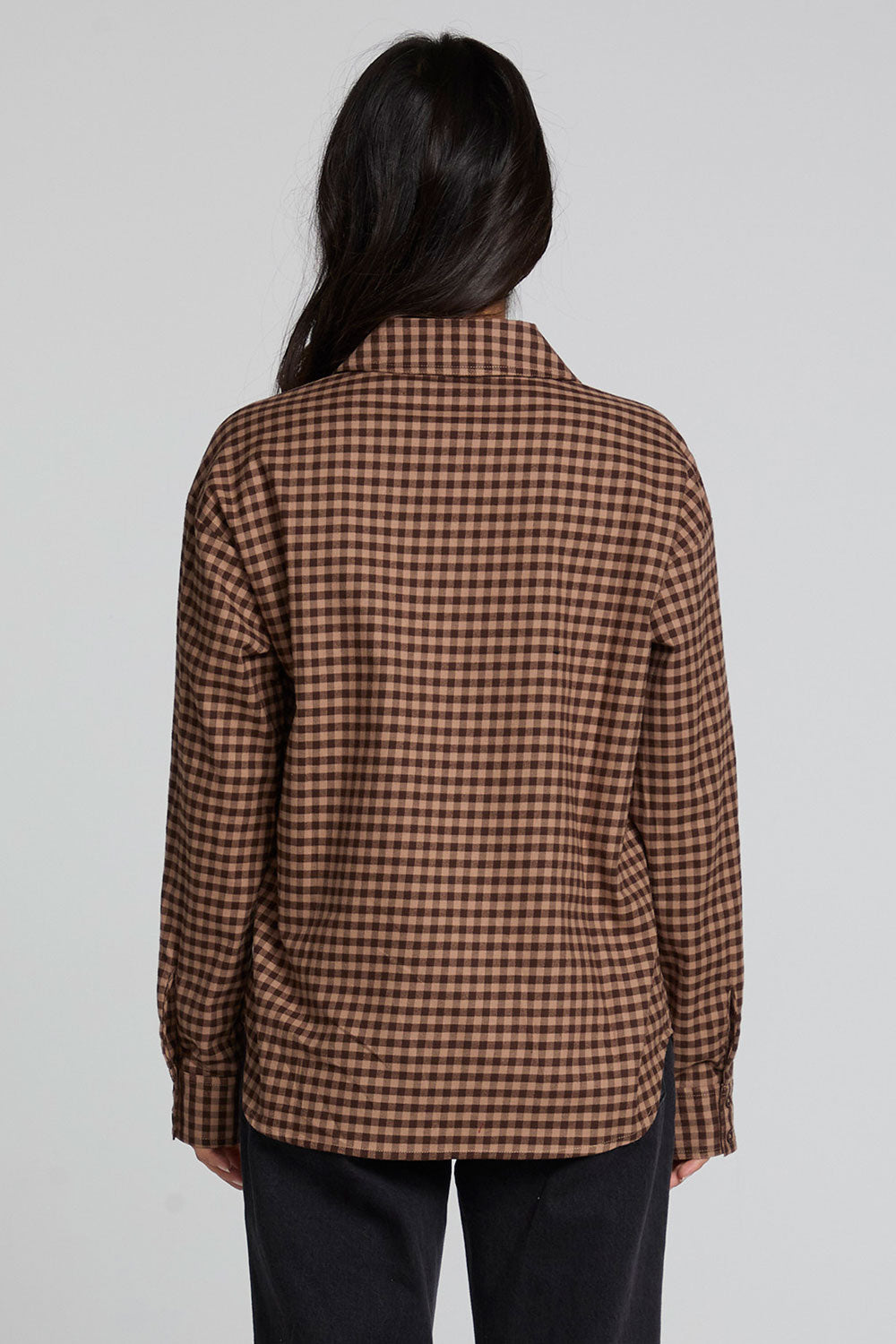 Back view of a woman wearing the Chaser Pine button down on a neutral background with arms down